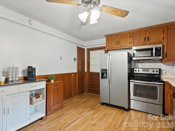 a kitchen with stainless steel appliances granite countertop a refrigerator a stove a sink and dishwasher with wooden floor