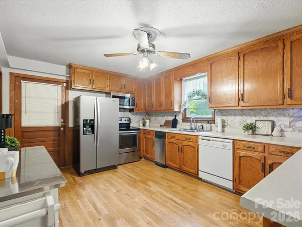 a kitchen with stainless steel appliances granite countertop a refrigerator a sink dishwasher a stove with wooden cabinets and floor