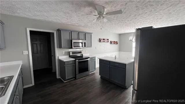 a kitchen with stainless steel appliances granite countertop a refrigerator a stove a sink dishwasher and a oven with wooden floor