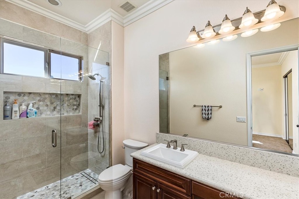 39110 Loren Way Temecula, CA 92592 - Photo 21 of 42 a bathroom with a granite countertop sink toilet a large mirror a shower and vanity