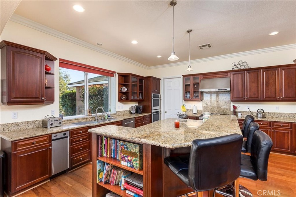 39110 Loren Way Temecula, CA 92592 - Photo 8 of 42 a kitchen with stainless steel appliances granite countertop a table chairs sink refrigerator and cabinets