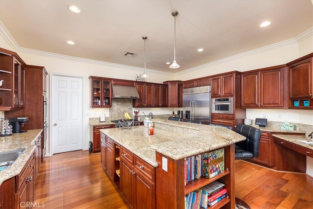 39110 Loren Way Temecula, CA 92592 - Photo 9 of 42 a kitchen with kitchen island a stove a sink a oven and a refrigerator with wooden cabinets
