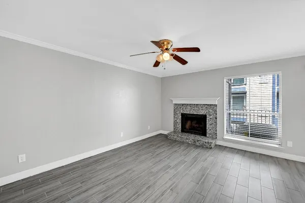 a view of an empty room with a window and wooden floor