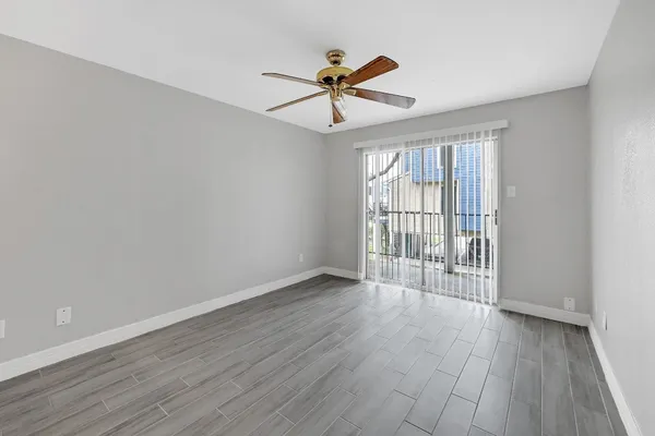 a view of empty room with wooden floor and ceiling fan