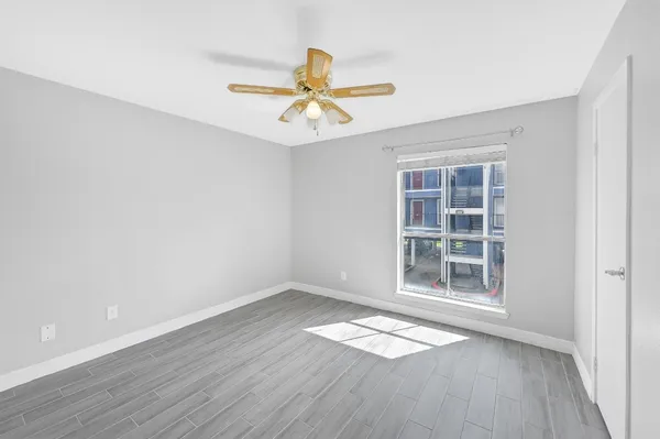 a view of an empty room with window and a ceiling fan