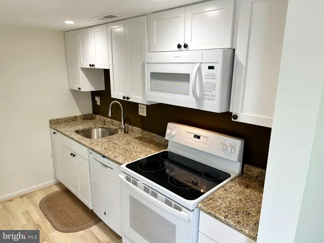 a view of kitchen with refrigerator stove and wooden floor