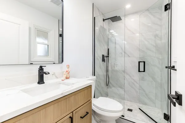 a bathroom with a sink a toilet a mirror and shower