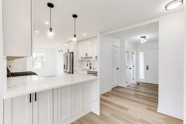a large white kitchen with kitchen island a sink stainless steel appliances and cabinets