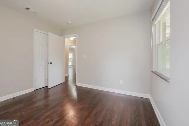 a view of an empty room with wooden floor and a window