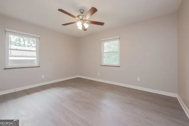 an empty room with wooden floor and windows