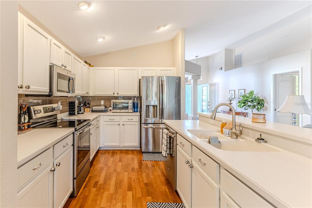 150 Gordham Court Spring Hill, FL 34609 - Photo 24 of 71 a kitchen with a sink dishwasher a refrigerator and white cabinets with wooden floor