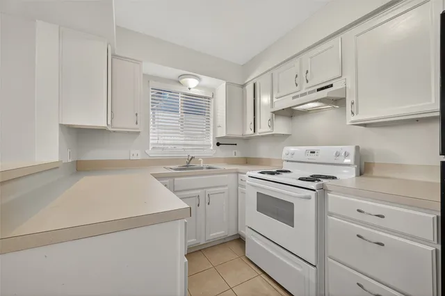 a kitchen with cabinets appliances a sink and a window