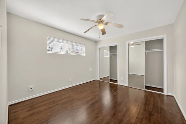 an empty room with wooden floor ceiling fan