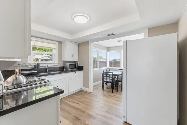 a kitchen with stainless steel appliances granite countertop a stove a sink and a microwave