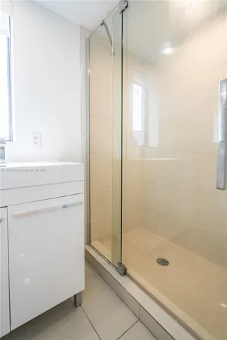a bathroom with a shower a mirror and a glass door