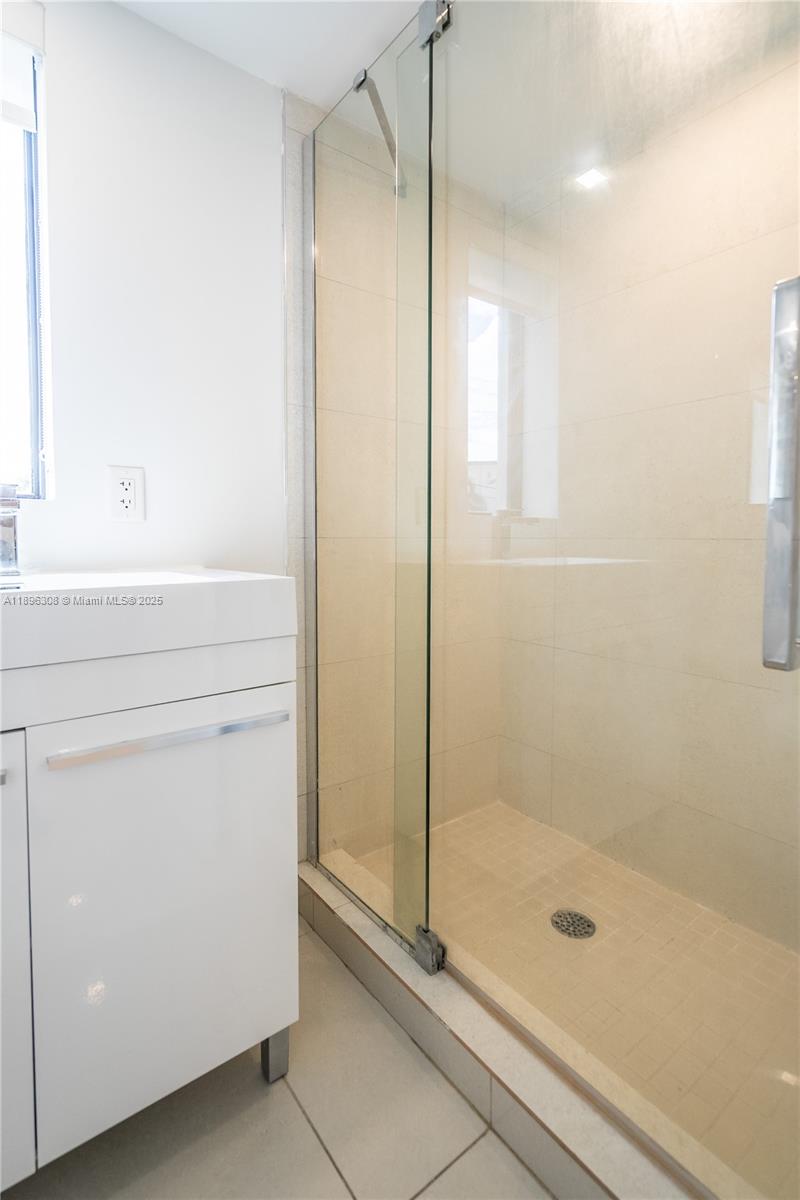 1971 Bay Drive, Unit 102 Miami Beach, FL 33141 - Photo 17 of 24 a bathroom with a shower a mirror and a glass door