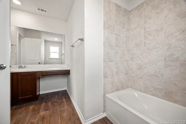 a bathroom with a tub sink and mirror