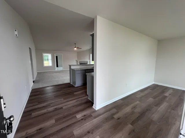 a view of kitchen and empty room with wooden floor