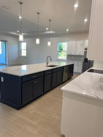 a large kitchen with a large counter top space a sink stainless steel appliances and cabinets