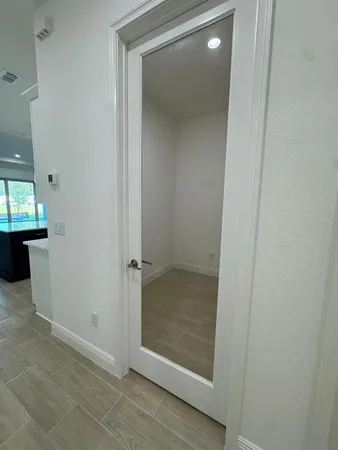an empty room with wooden floor mirror and windows