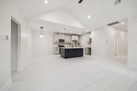 a large white kitchen with kitchen island a stove a refrigerator a sink and a counter top space