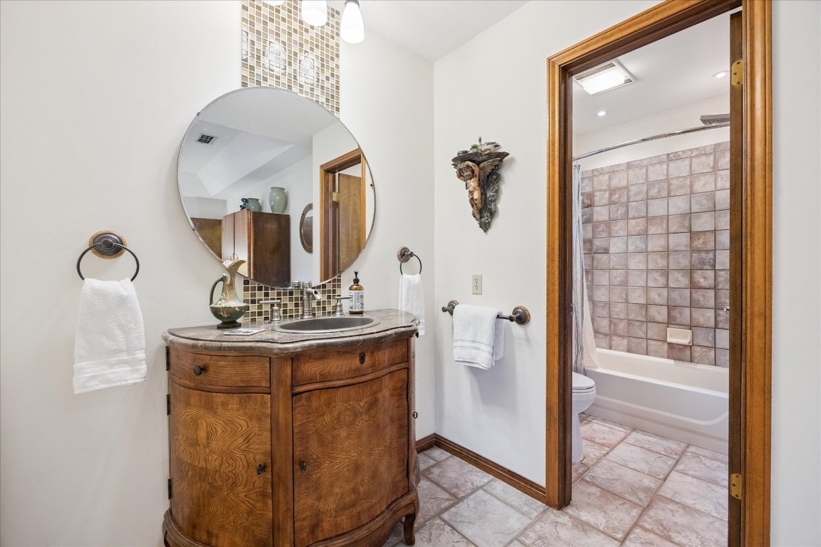 7806 Comanche Trail Leander, TX 78641 - Photo 21 of 32 a bathroom with a mirror a sink and a shower