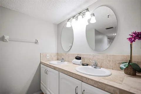 a bathroom with a double vanity sink mirror and shower