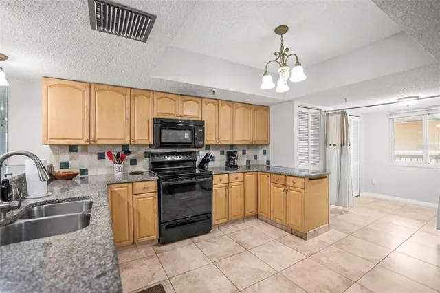 a kitchen with granite countertop a refrigerator and a stove top oven