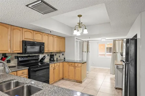 a kitchen with stainless steel appliances granite countertop a stove top oven a sink dishwasher a dining table and chairs with wooden floor