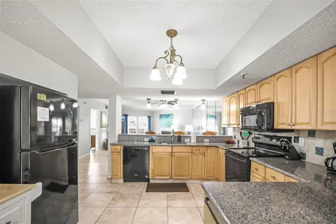 a kitchen with stainless steel appliances granite countertop a refrigerator a sink dishwasher a stove and white cabinets with wooden floor