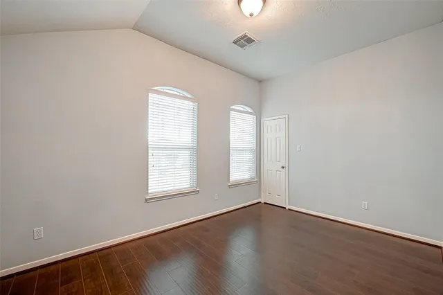 an empty room with wooden floor and windows