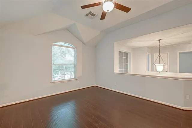 a view of an empty room with chandelier fan and a window