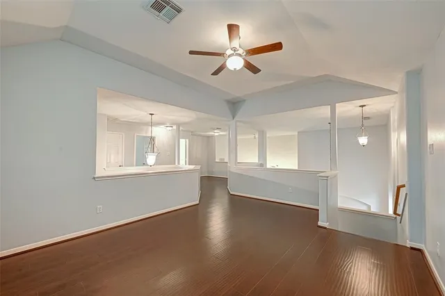 an empty room with wooden floor fan and windows