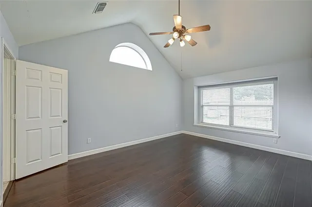 an empty room with wooden floor chandelier fan and windows