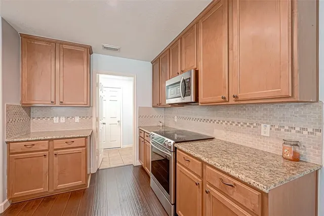 a kitchen with stainless steel appliances granite countertop a stove a sink and a microwave