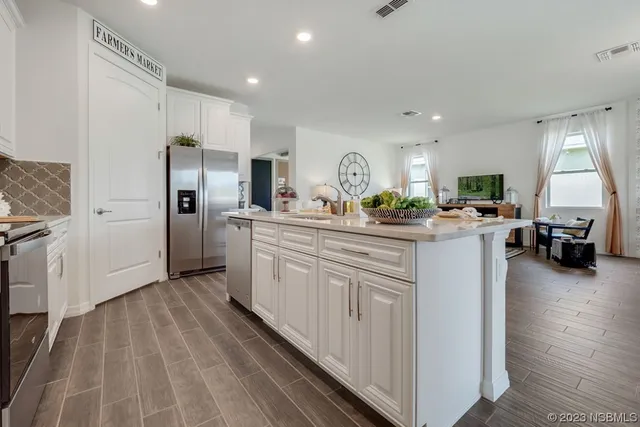 a kitchen with stainless steel appliances kitchen island granite countertop a refrigerator a sink dishwasher and white cabinets with wooden floor