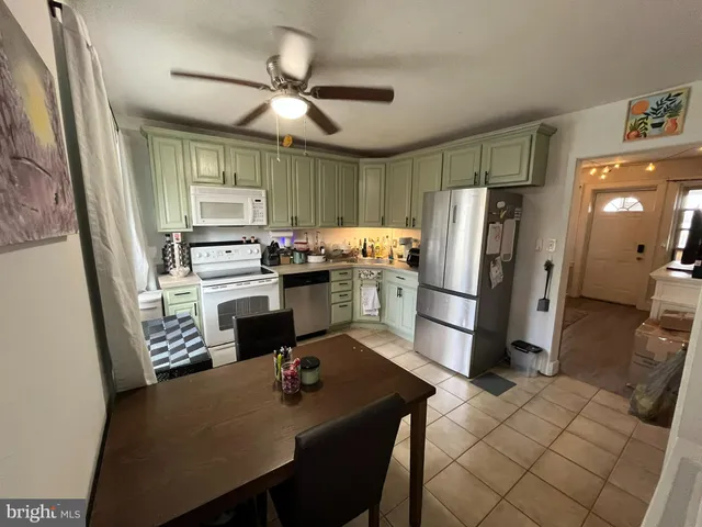 a kitchen with stainless steel appliances a refrigerator a sink a stove a dining table and chairs