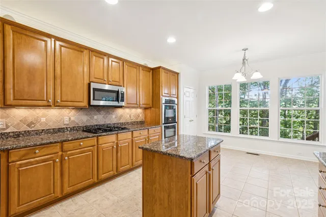 a large kitchen with granite countertop a stove a sink dishwasher a microwave oven with a large window