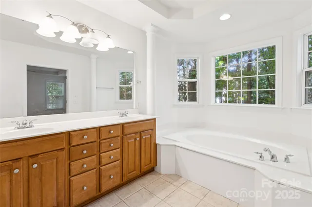 a spacious bathroom with a tub sink and mirror