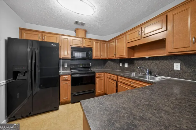 a kitchen with stainless steel appliances granite countertop a refrigerator a stove a sink and dishwasher