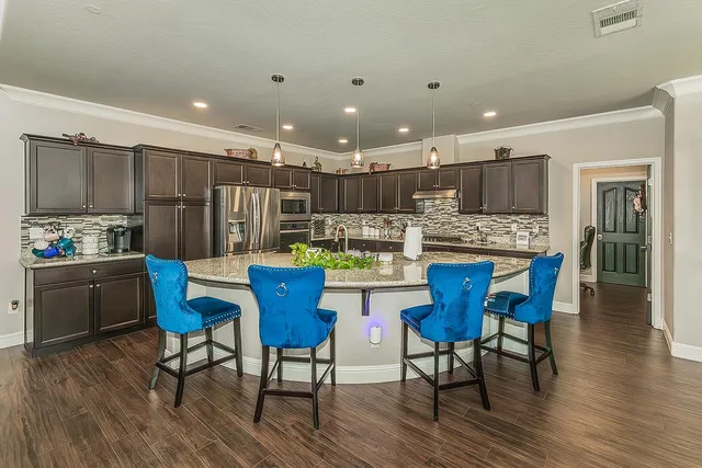 a kitchen with kitchen island granite countertop wooden floors and white stainless steel appliances