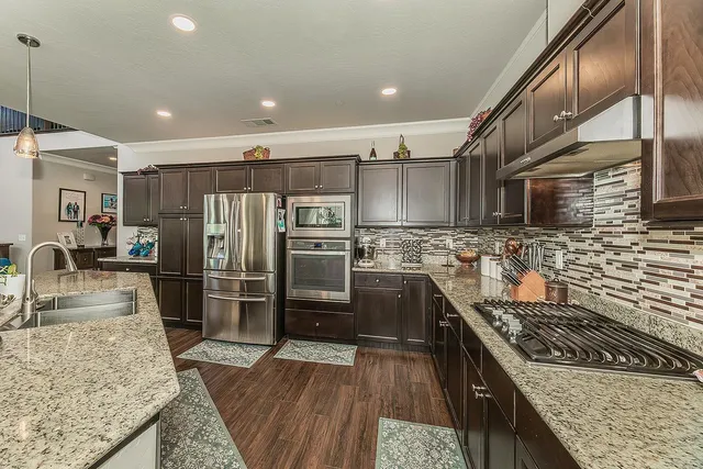a kitchen with stainless steel appliances granite countertop a refrigerator a stove and a sink