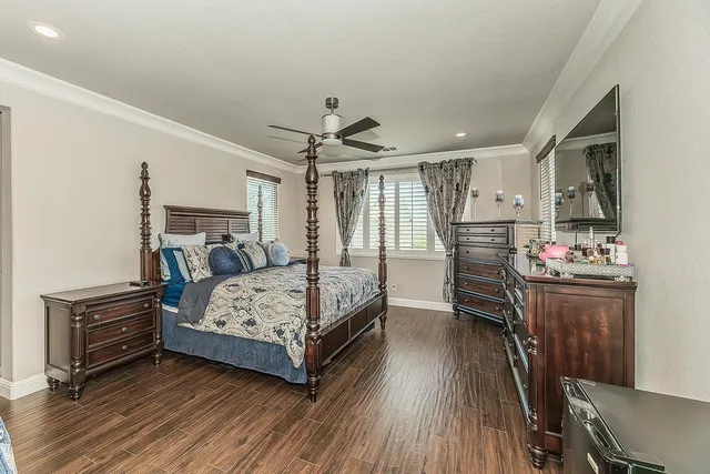 a bedroom with a bed next to a desk with wooden floor