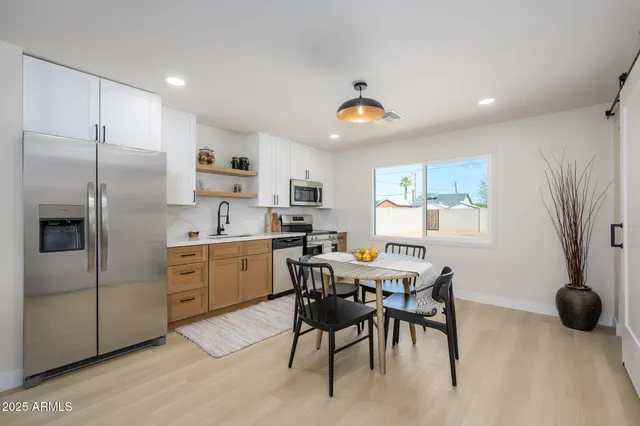 a kitchen with stainless steel appliances granite countertop a sink a stove a refrigerator cabinets a dining table and chairs