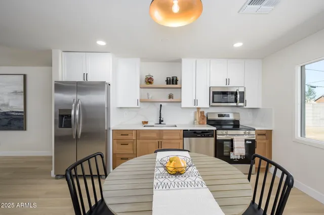 a kitchen with stainless steel appliances granite countertop a stove top oven a sink dishwasher a dining table and chairs with wooden floor