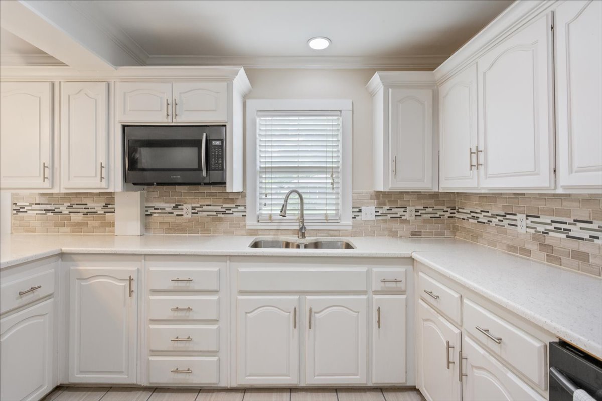 1607 North Harding Avenue Cameron, TX 76520 - Photo 14 of 37 White cabinetry and stone-look countertops define this well-appointed kitchen.