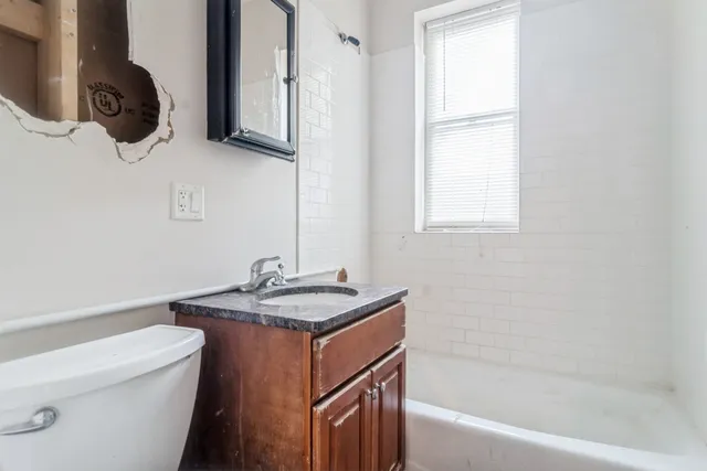 a bathroom with a granite countertop sink a toilet and bathtub