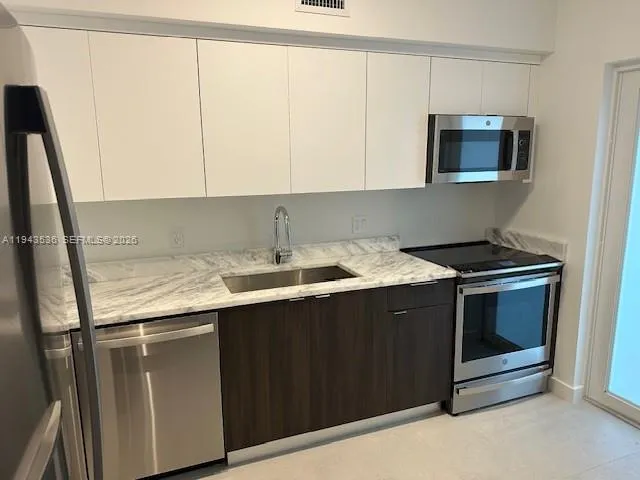 a kitchen with stainless steel appliances granite countertop a sink stove and microwave