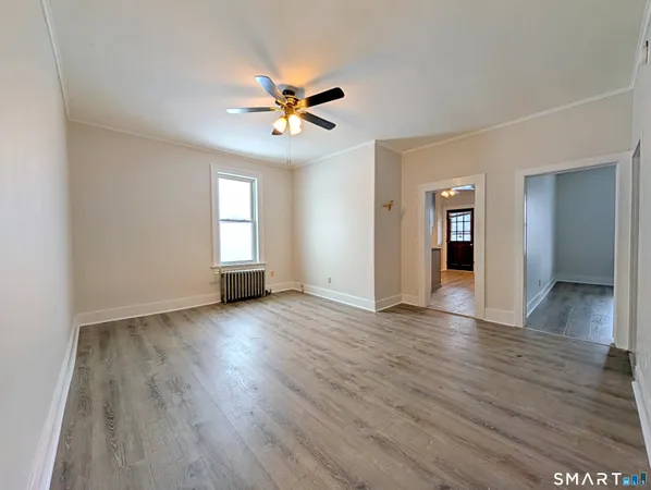 a view of empty room with wooden floor and window
