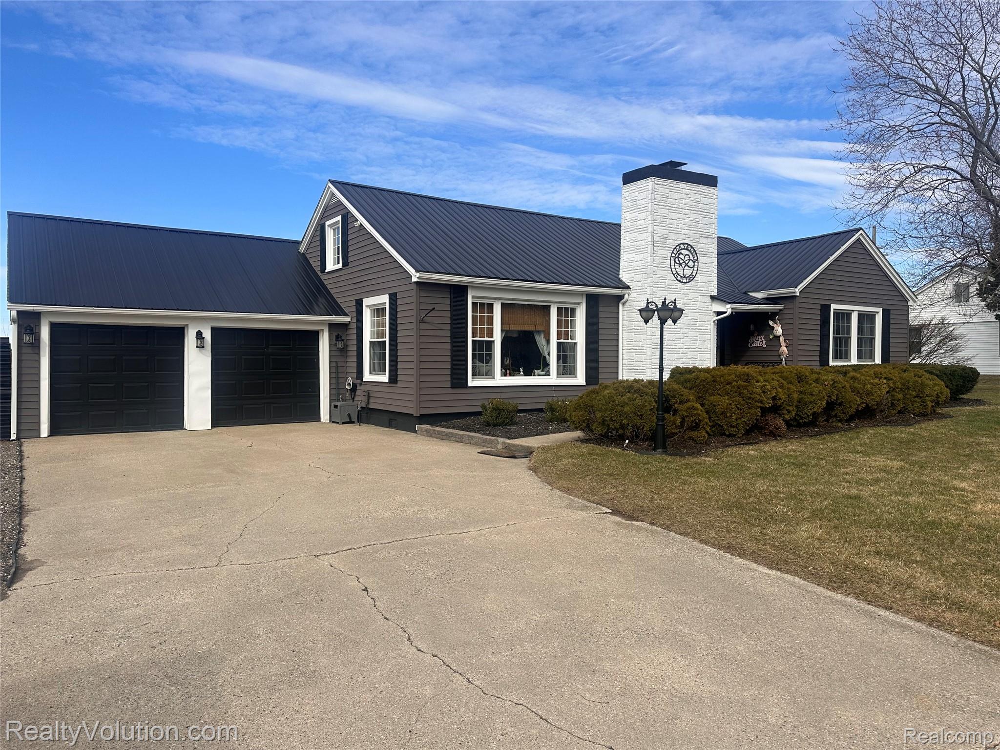 3034 West Oregon Road Lapeer, MI 48446 - Photo 1 of 29 Ranch-style home featuring a metal roof, concrete driveway, a chimney, and an attached garage